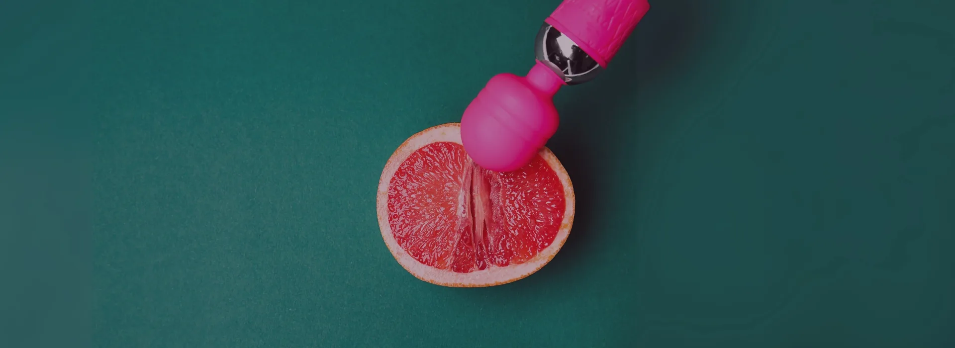 Vibrador rosa sobre media toronja en fondo verde, imagen sugerente para la categoría de vibradores en la tienda erótica Karmasex.es.